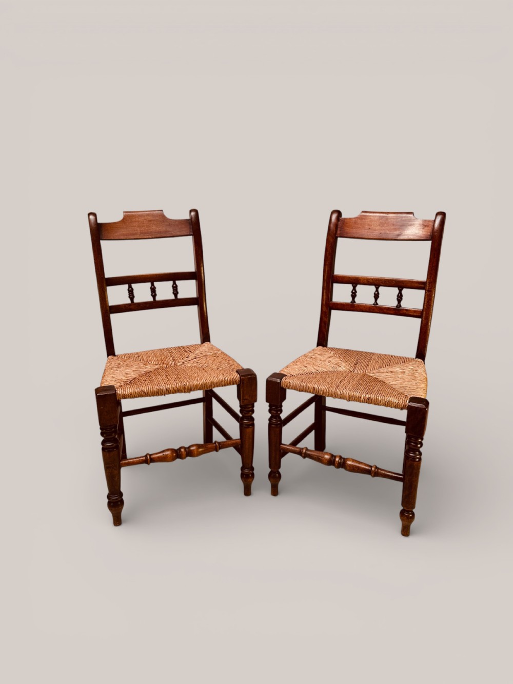 A set of dark ash and alder wood dining chairs featuring hand-woven rush seats, turned front legs, and decorative back spindles. View III