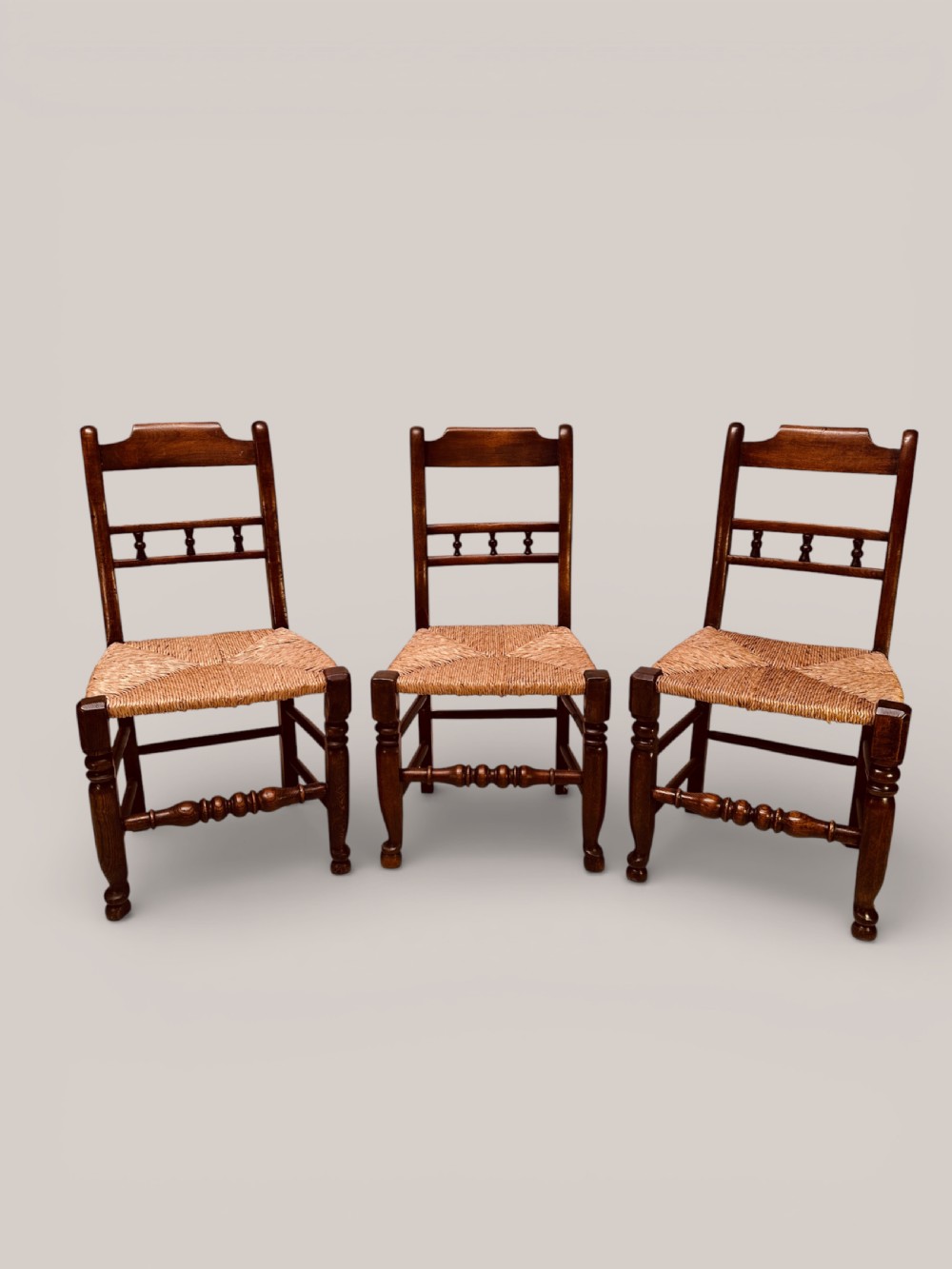 A set of dark ash and alder wood dining chairs featuring hand-woven rush seats, turned front legs, and decorative back spindles. View IV