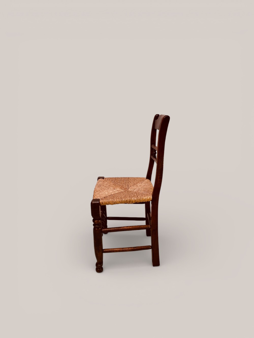 A set of dark ash and alder wood dining chairs featuring hand-woven rush seats, turned front legs, and decorative back spindles. View V