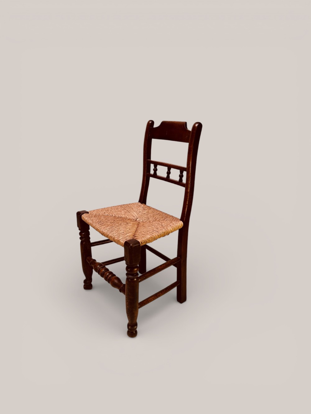 A set of dark ash and alder wood dining chairs featuring hand-woven rush seats, turned front legs, and decorative back spindles. View VI