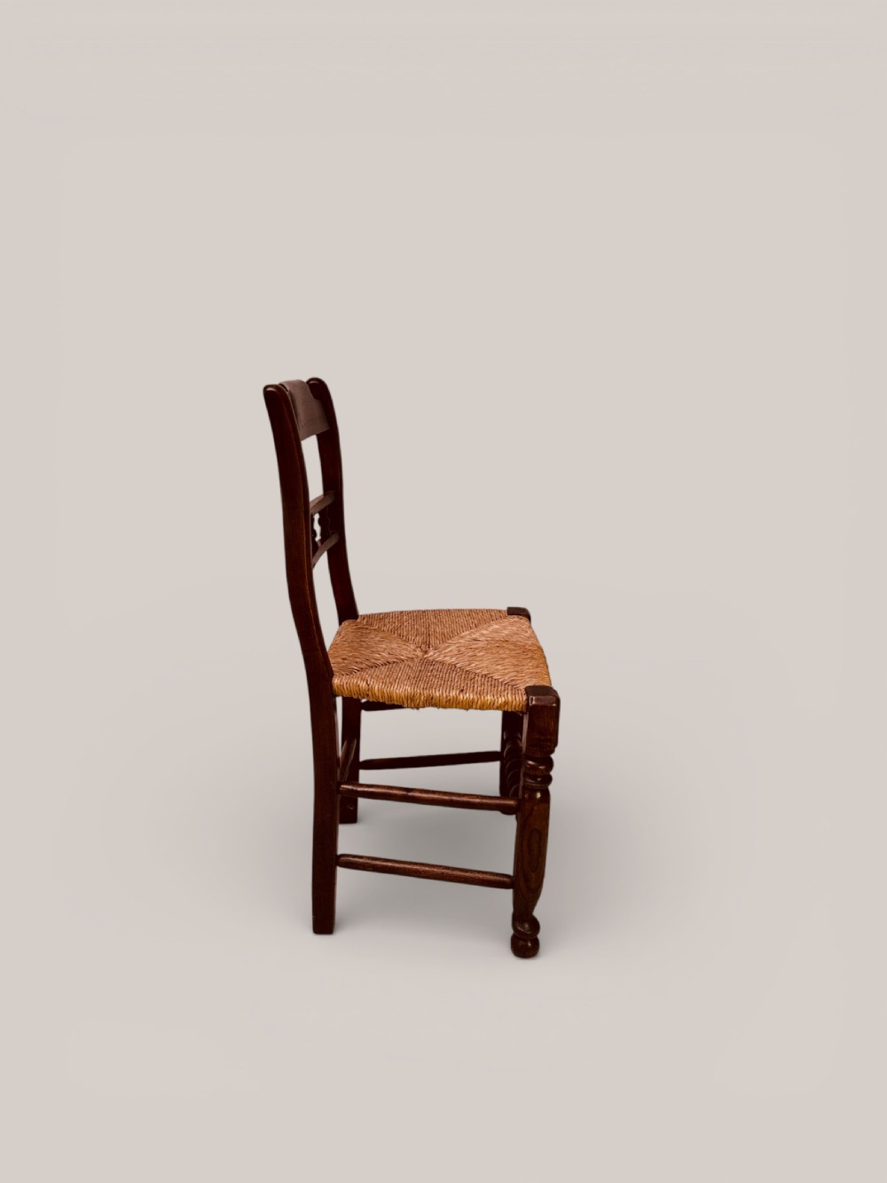 A set of dark ash and alder wood dining chairs featuring hand-woven rush seats, turned front legs, and decorative back spindles. View VII
