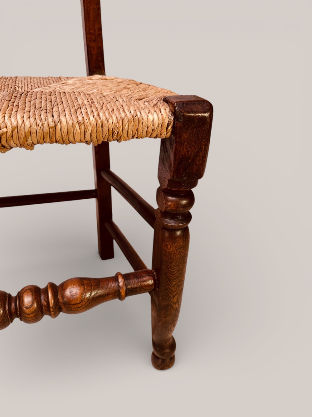 A set of dark ash and alder wood dining chairs featuring hand-woven rush seats, turned front legs, and decorative back spindles. View XI