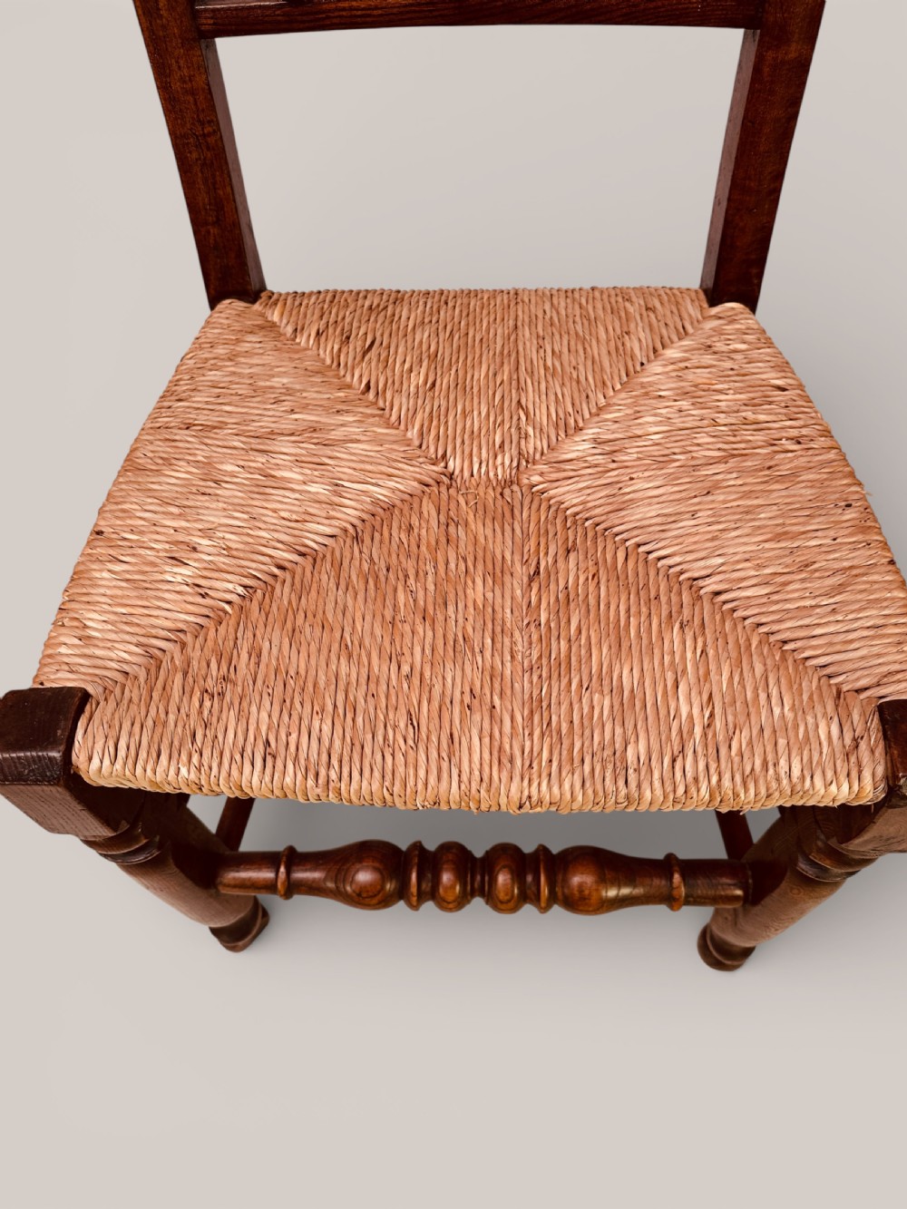A set of dark ash and alder wood dining chairs featuring hand-woven rush seats, turned front legs, and decorative back spindles. View XII