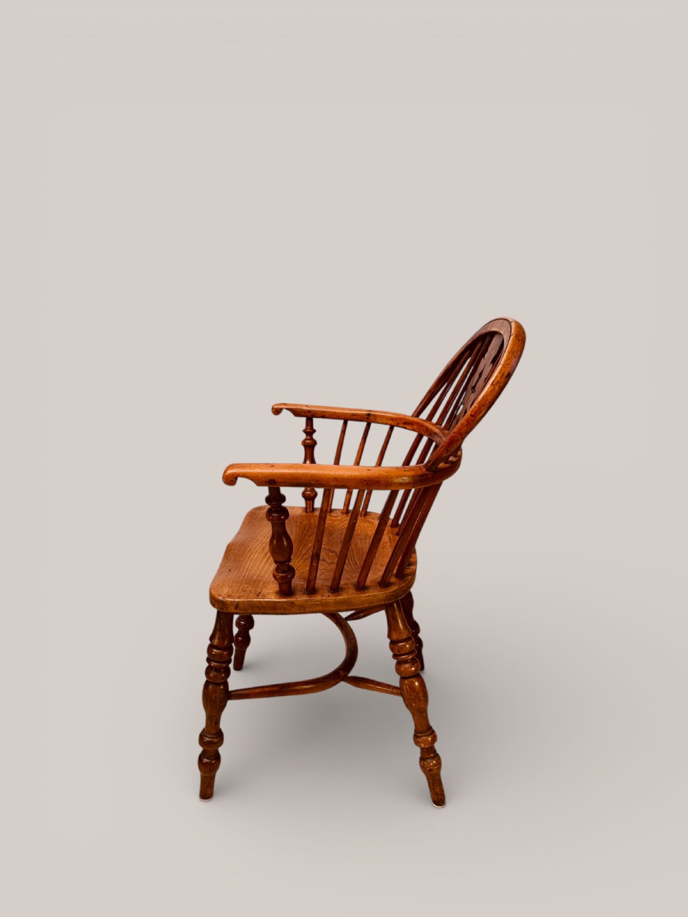 A Victorian 19th-century Windsor low back armchair constructed from yew and elm wood featuring turned legs, a pierced splat, and a contoured saddle seat. View V