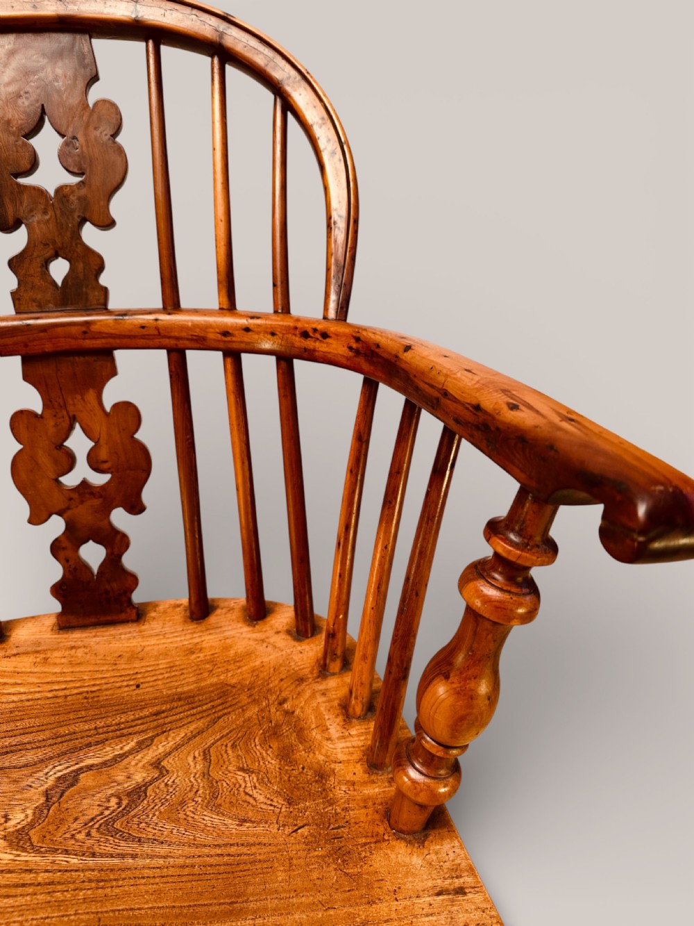 A Victorian 19th-century Windsor low back armchair constructed from yew and elm wood featuring turned legs, a pierced splat, and a contoured saddle seat. View VI
