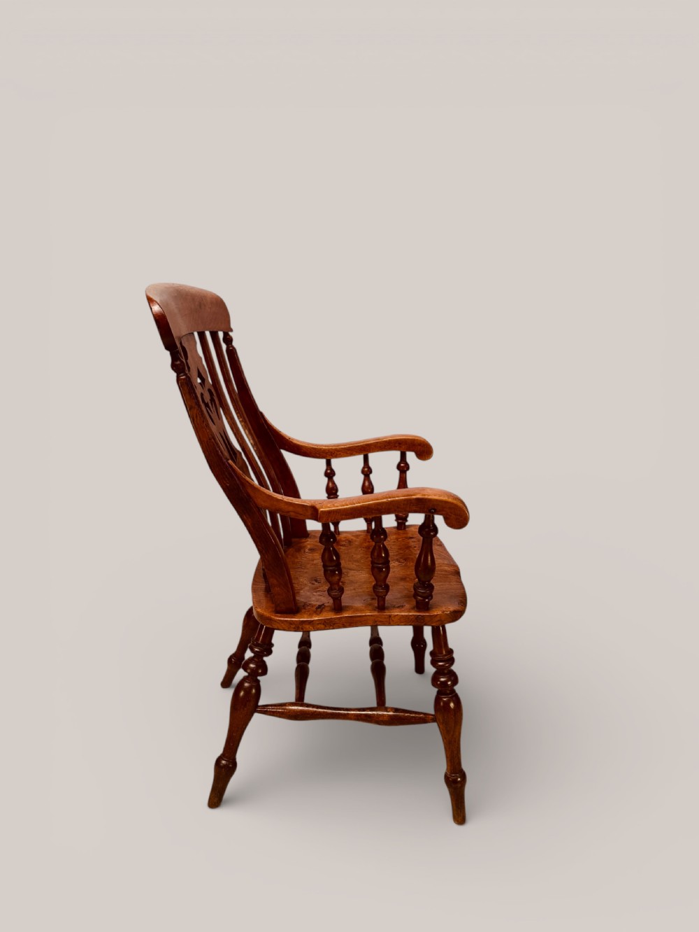 A Victorian Windsor armchair crafted from beech and elm with a pierced back splat, turned legs, and curved armrests. View V
