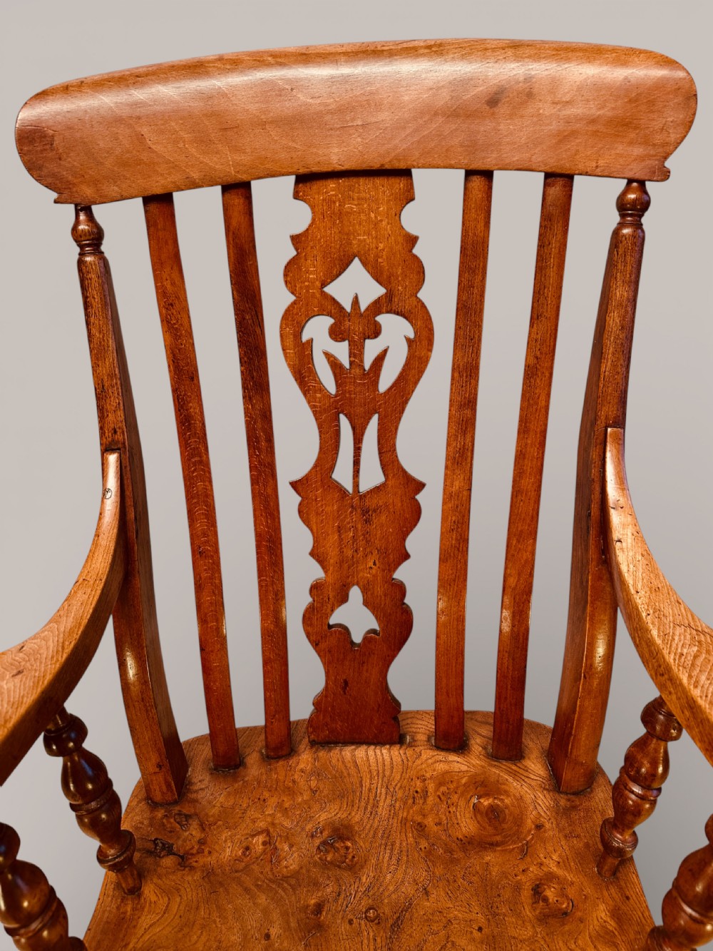 A Victorian Windsor armchair crafted from beech and elm with a pierced back splat, turned legs, and curved armrests. View VI