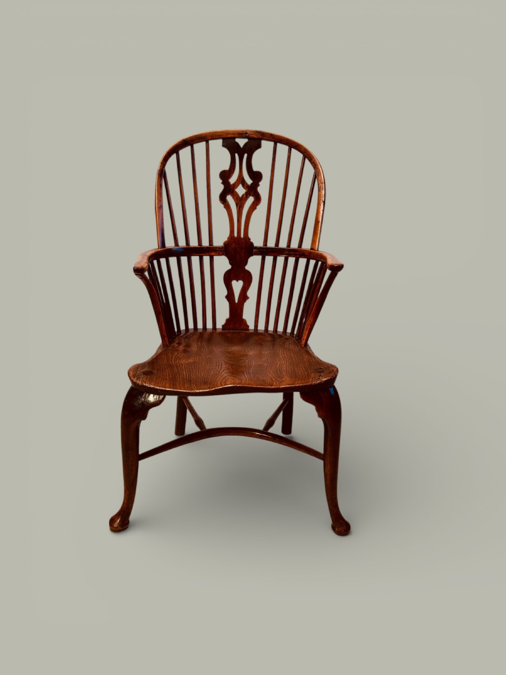 An eighteenth-century Windsor armchair crafted from yew wood and elm featuring a curved hoop back, pierced splat, shaped saddle seat, and cabriole front legs.