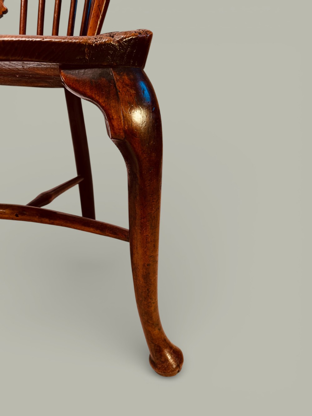 An eighteenth-century Windsor armchair crafted from yew wood and elm featuring a curved hoop back, pierced splat, shaped saddle seat, and cabriole front legs. View X