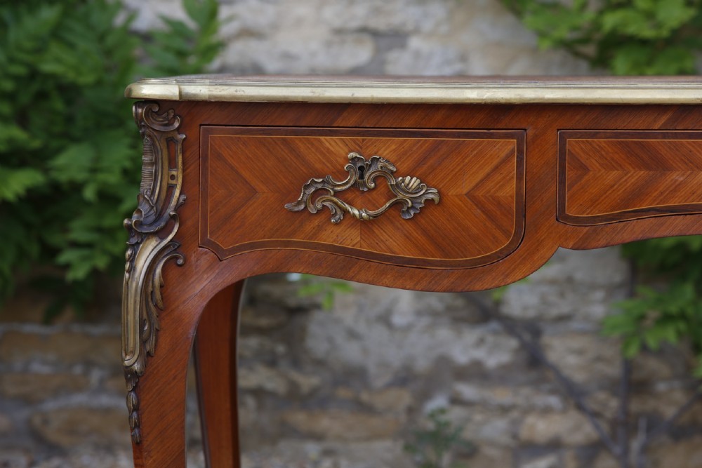 A Louis XV style bureau plat writing desk crafted from rosewood and tulipwood parquetry veneer, featuring gilt-bronze mounts, cabriole legs, three frieze drawers, and a leather-inset writing top. View III