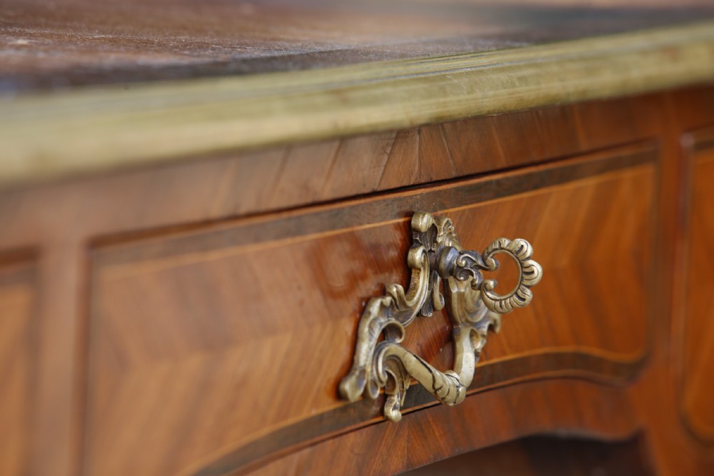 A Louis XV style bureau plat writing desk crafted from rosewood and tulipwood parquetry veneer, featuring gilt-bronze mounts, cabriole legs, three frieze drawers, and a leather-inset writing top. View V