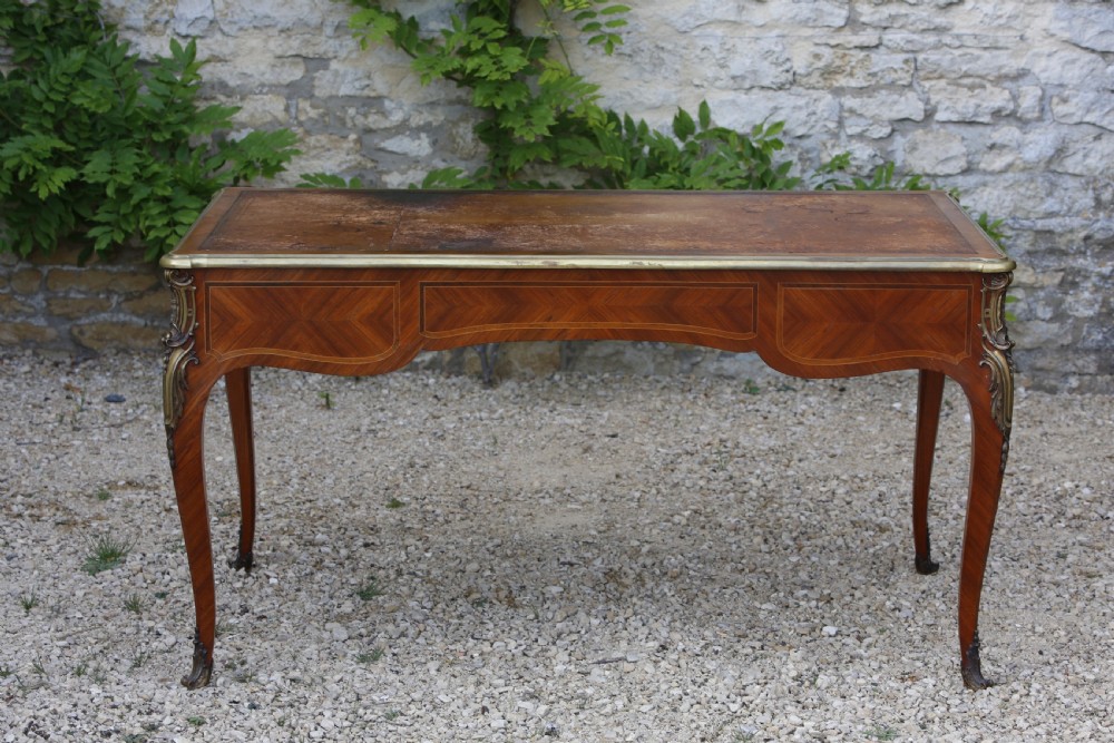 A Louis XV style bureau plat writing desk crafted from rosewood and tulipwood parquetry veneer, featuring gilt-bronze mounts, cabriole legs, three frieze drawers, and a leather-inset writing top. View VIII