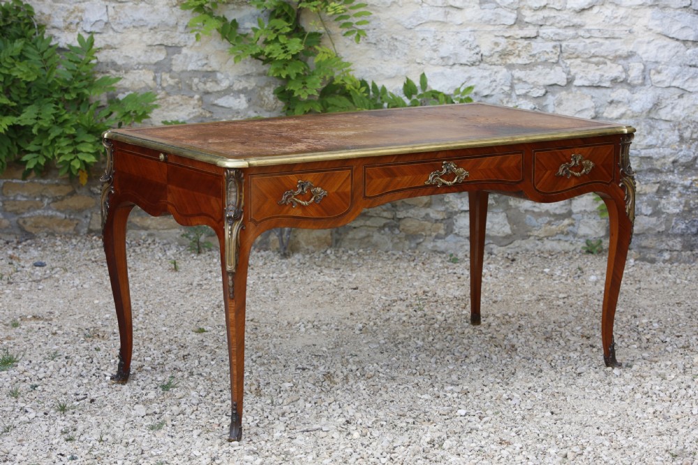 A Louis XV style bureau plat writing desk crafted from rosewood and tulipwood parquetry veneer, featuring gilt-bronze mounts, cabriole legs, three frieze drawers, and a leather-inset writing top. View XII