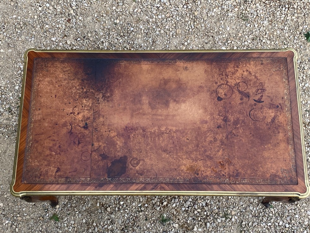A Louis XV style bureau plat writing desk crafted from rosewood and tulipwood parquetry veneer, featuring gilt-bronze mounts, cabriole legs, three frieze drawers, and a leather-inset writing top. View XIV