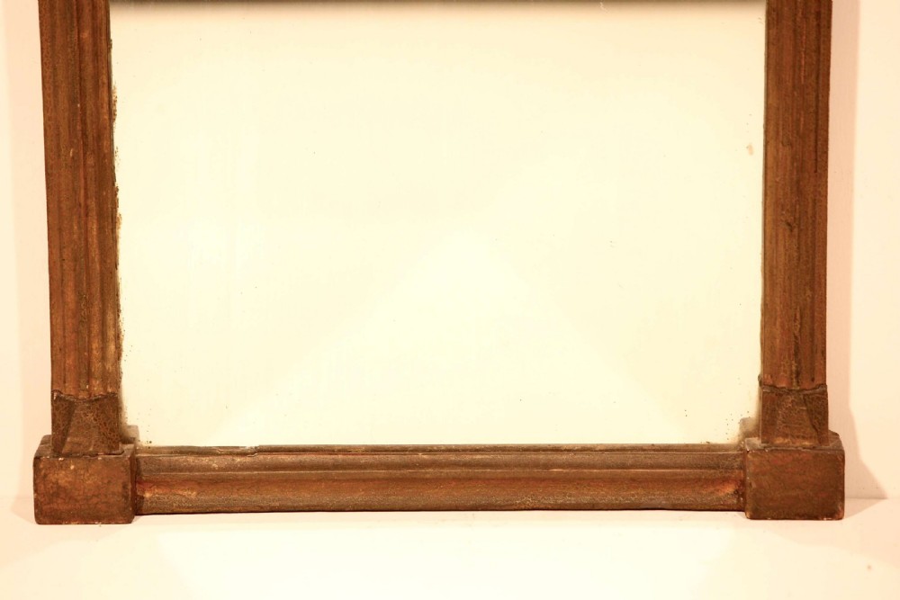 An antique Regency giltwood pier mirror featuring fluted side columns, a sphere-ornamented upper cornice, and a reverse-painted landscape scene on the top panel. View IX