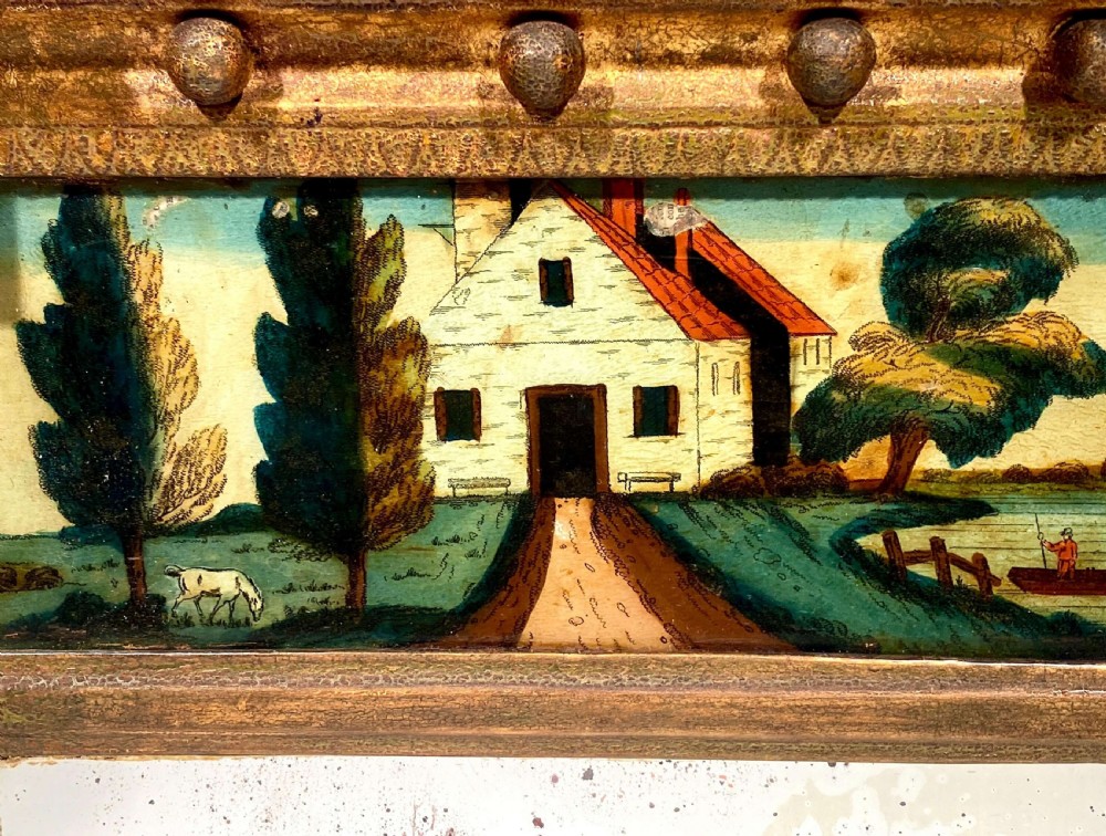 An antique Regency giltwood pier mirror featuring fluted side columns, a sphere-ornamented upper cornice, and a reverse-painted landscape scene on the top panel. View XI