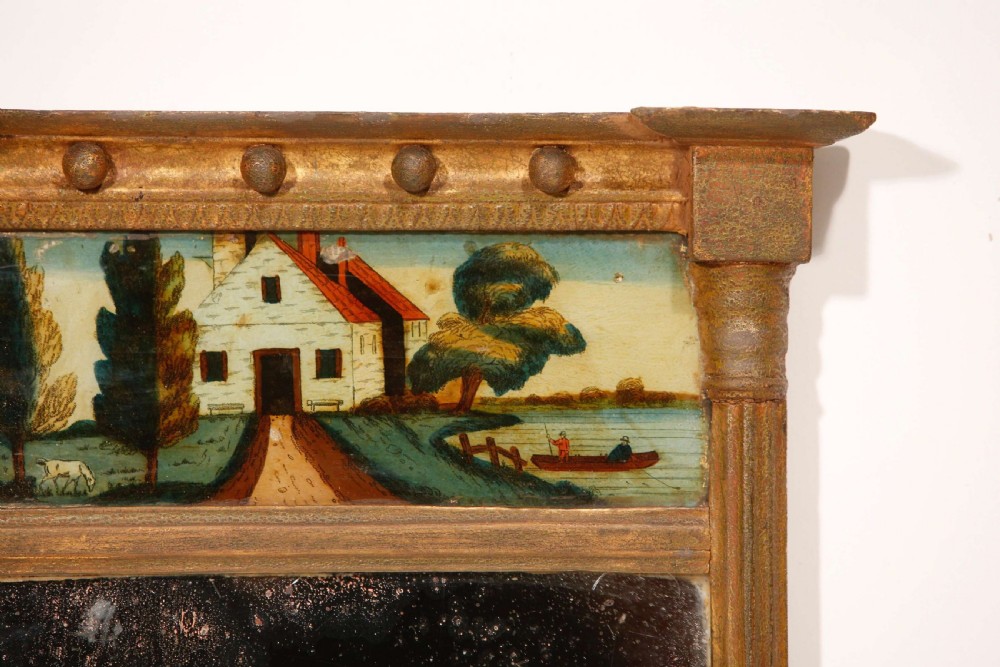 An antique Regency giltwood pier mirror featuring fluted side columns, a sphere-ornamented upper cornice, and a reverse-painted landscape scene on the top panel. View XIV