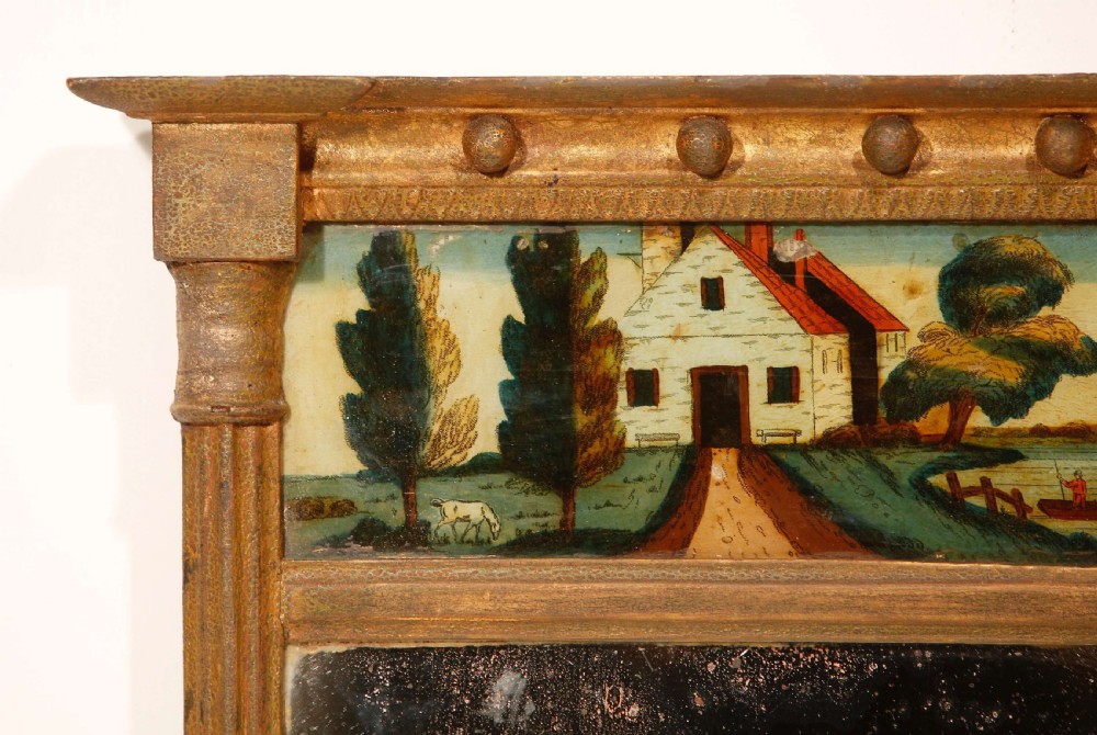 An antique Regency giltwood pier mirror featuring fluted side columns, a sphere-ornamented upper cornice, and a reverse-painted landscape scene on the top panel. View XXVI