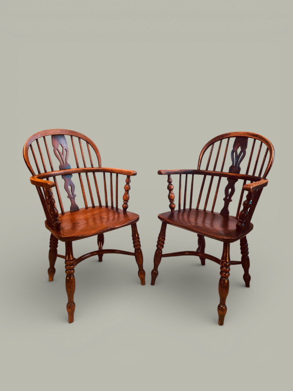 A set of twelve antique low back Windsor armchairs crafted from warm brown ash and elm with turned legs and hoop backs. View XII