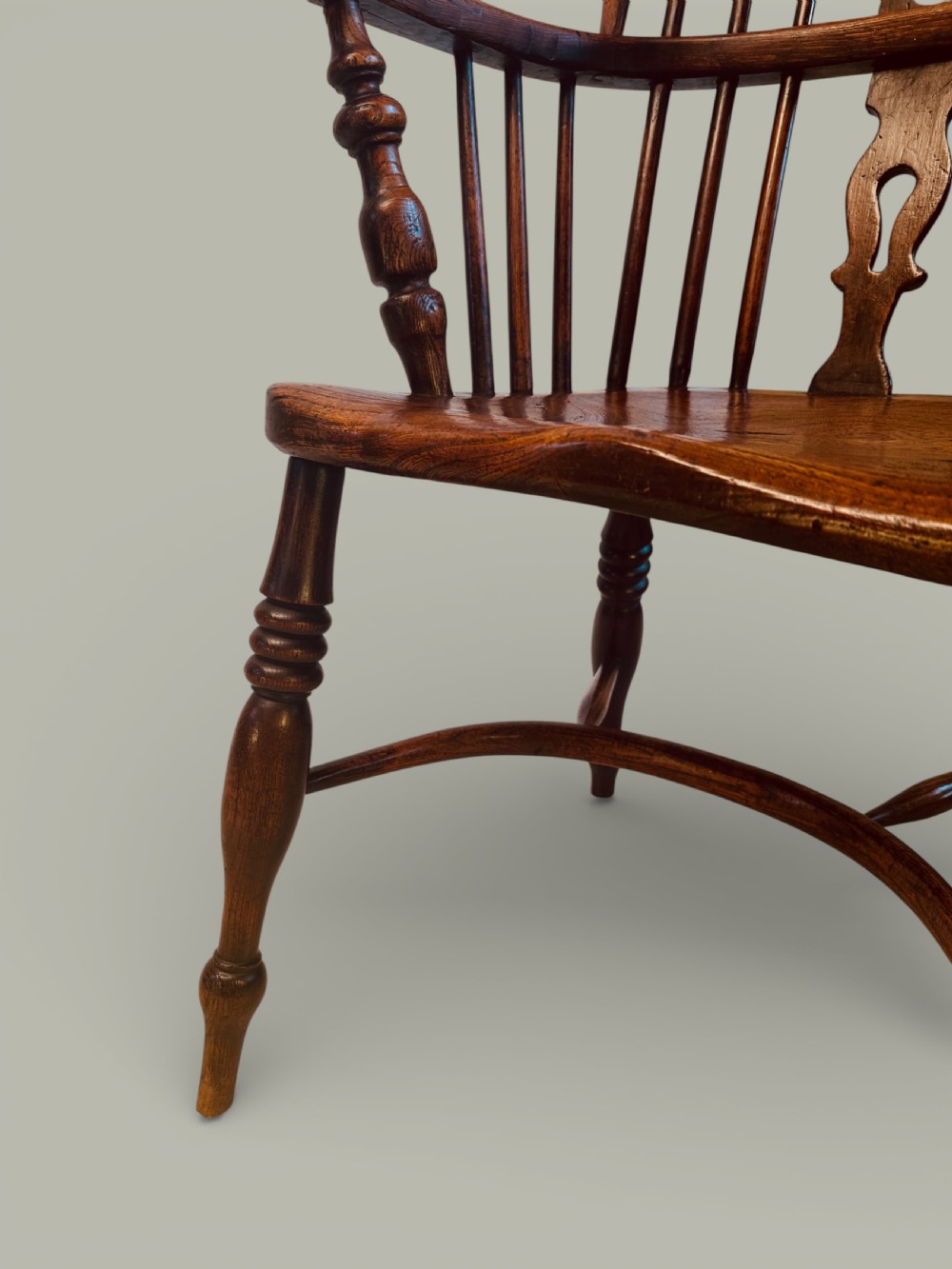 A set of twelve antique low back Windsor armchairs crafted from warm brown ash and elm with turned legs and hoop backs. View XIV