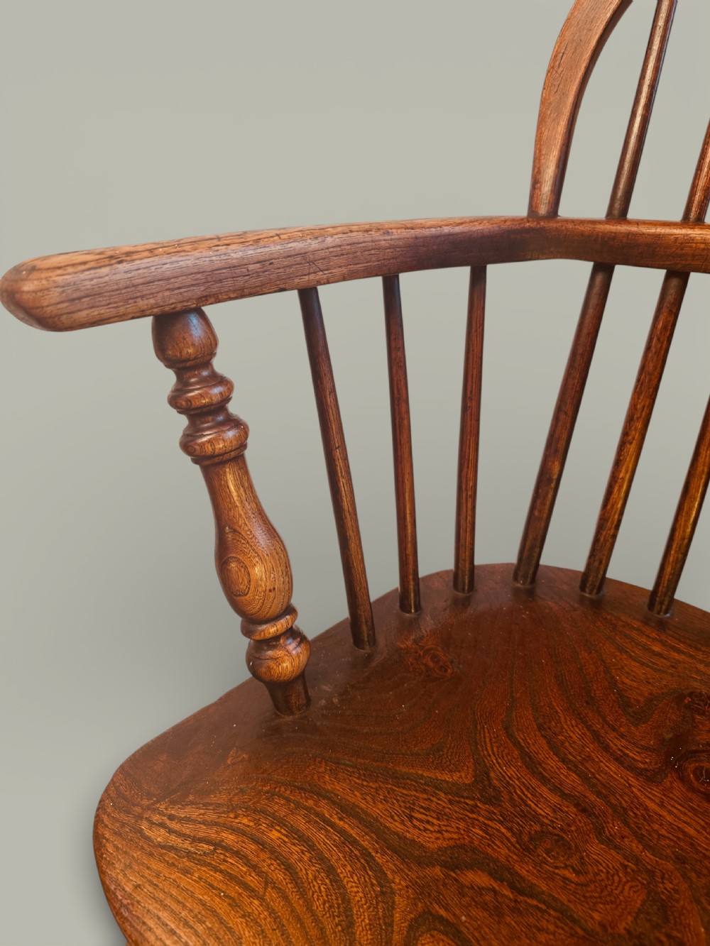 A set of twelve antique low back Windsor armchairs crafted from warm brown ash and elm with turned legs and hoop backs. View XV
