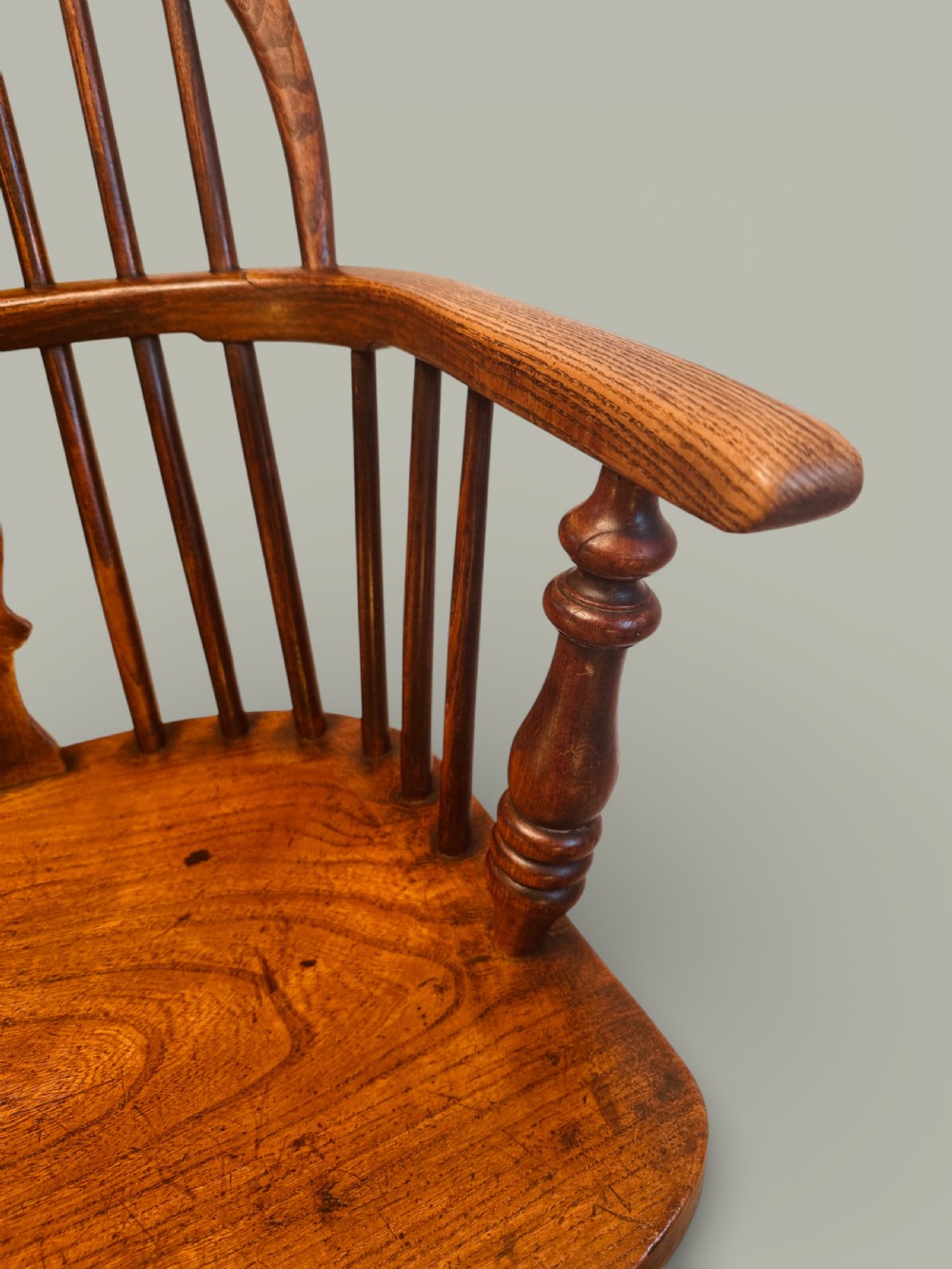 A set of twelve antique low back Windsor armchairs crafted from warm brown ash and elm with turned legs and hoop backs. View XVI