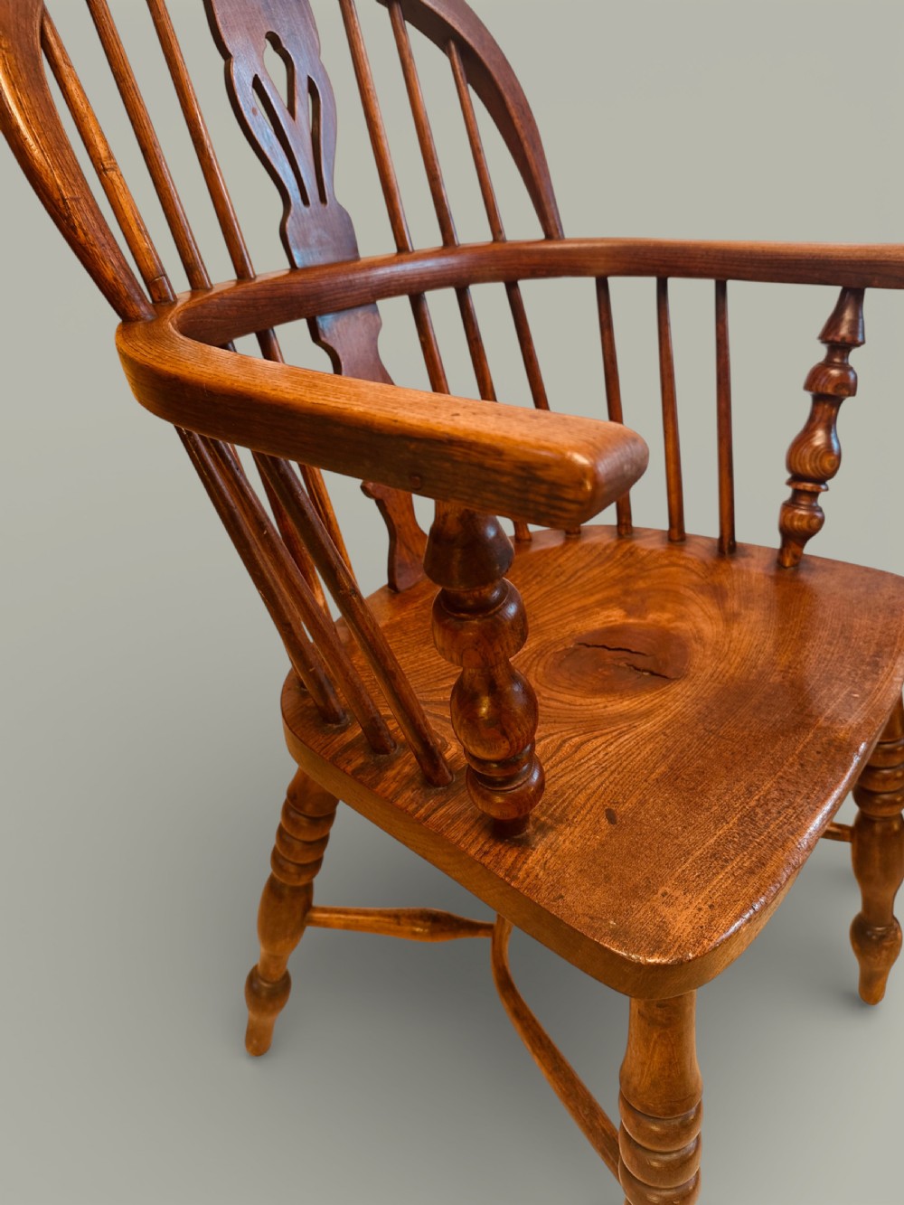 A set of twelve antique low back Windsor armchairs crafted from warm brown ash and elm with turned legs and hoop backs. View XVII