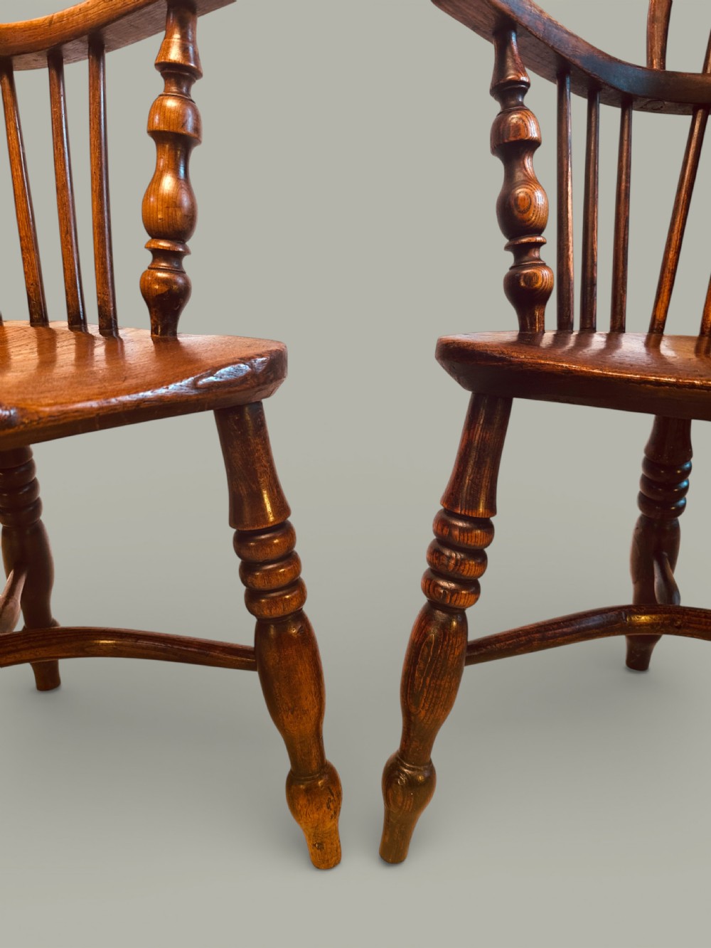 A set of twelve antique low back Windsor armchairs crafted from warm brown ash and elm with turned legs and hoop backs. View XIX
