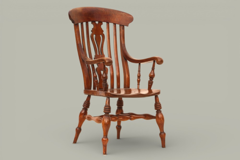 A late nineteenth-century Windsor armchair crafted from warm brown fruitwood and elm with turned legs, curved arms, and a central splat back.