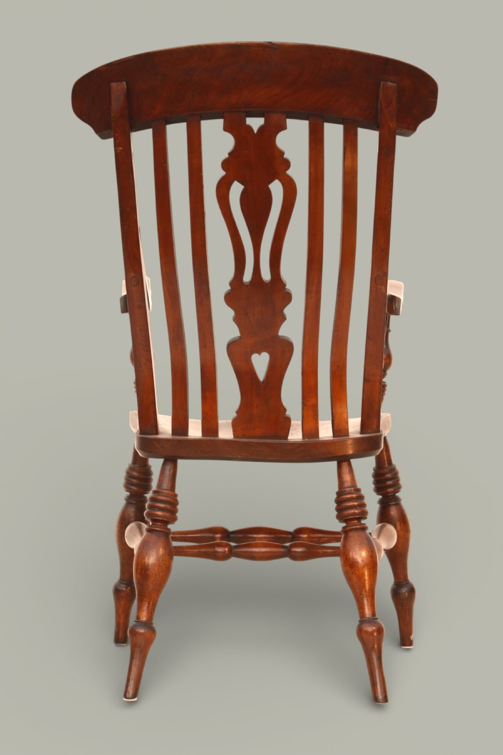 A late nineteenth-century Windsor armchair crafted from warm brown fruitwood and elm with turned legs, curved arms, and a central splat back. View V