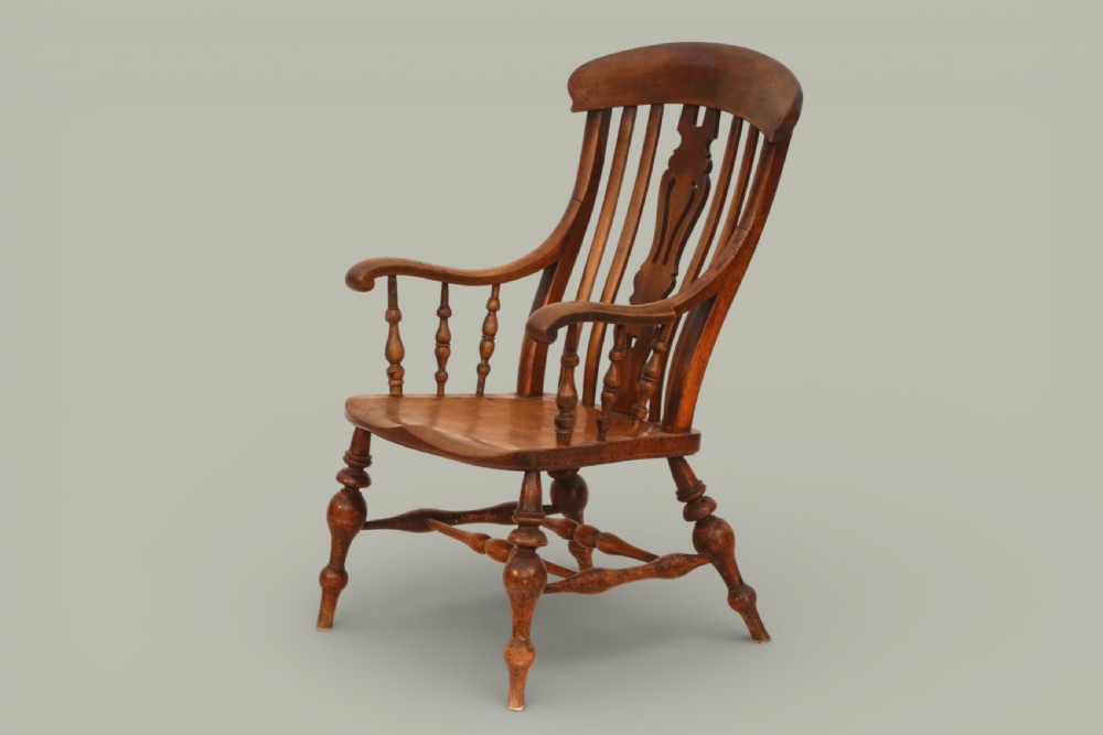 A late nineteenth-century British Windsor armchair made of warm brown elm and fruitwood with a shaped crest rail, pierced central splat, turned spindles, contoured saddle seat, and turned legs with stretchers. View II