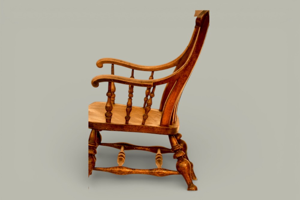 A late nineteenth-century British Windsor armchair made of warm brown elm and fruitwood with a shaped crest rail, pierced central splat, turned spindles, contoured saddle seat, and turned legs with stretchers. View III