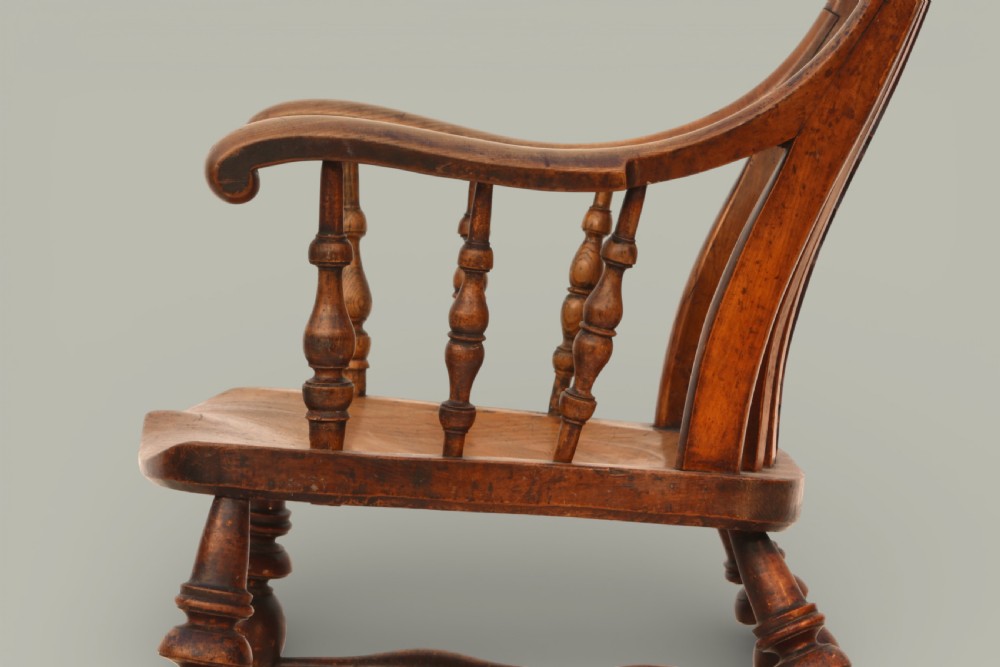 A late nineteenth-century British Windsor armchair made of warm brown elm and fruitwood with a shaped crest rail, pierced central splat, turned spindles, contoured saddle seat, and turned legs with stretchers. View VI