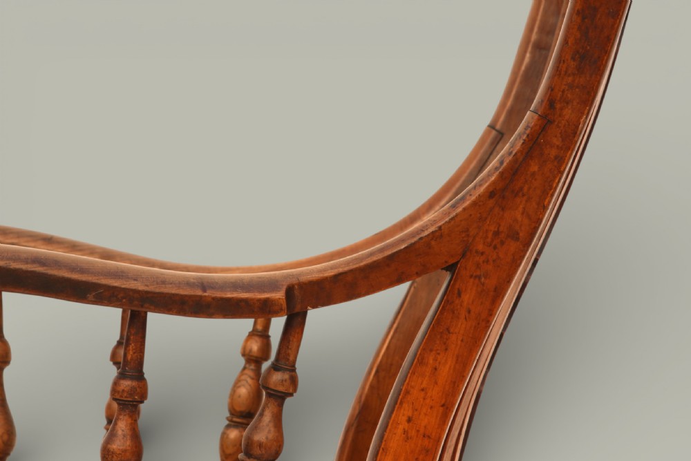 A late nineteenth-century British Windsor armchair made of warm brown elm and fruitwood with a shaped crest rail, pierced central splat, turned spindles, contoured saddle seat, and turned legs with stretchers. View VII