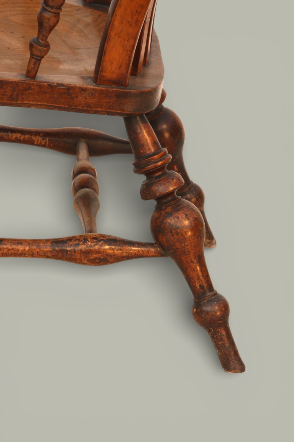 A late nineteenth-century British Windsor armchair made of warm brown elm and fruitwood with a shaped crest rail, pierced central splat, turned spindles, contoured saddle seat, and turned legs with stretchers. View VIII