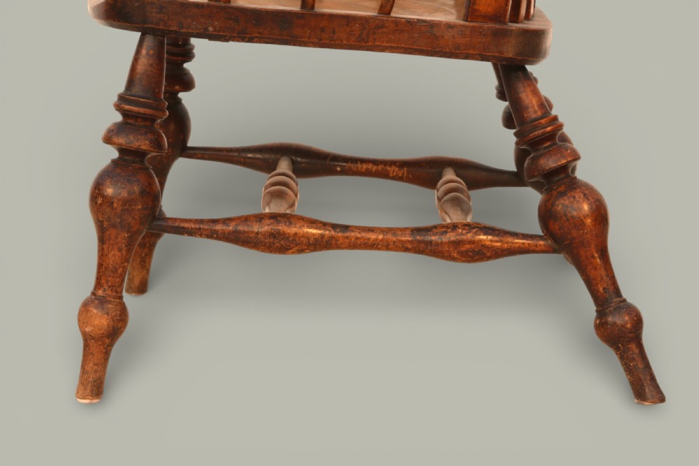 A late nineteenth-century British Windsor armchair made of warm brown elm and fruitwood with a shaped crest rail, pierced central splat, turned spindles, contoured saddle seat, and turned legs with stretchers. View IX