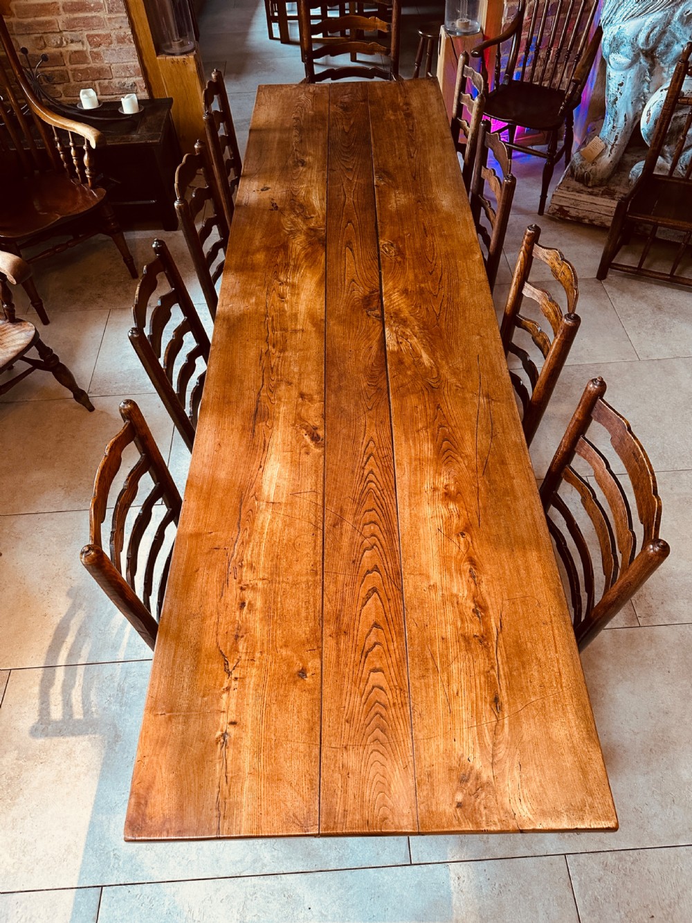 A long French elm farmhouse dining table featuring a three-plank wooden top with prominent grain patterns and square legs. View VI