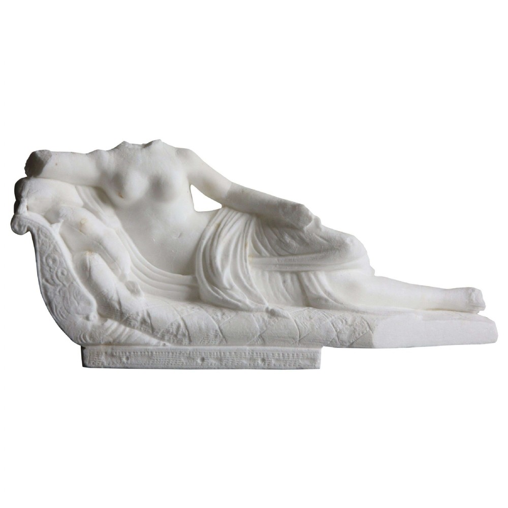 A carved white Carrara marble Neoclassical sculpture depicting a semi-draped reclining female figure on a classical couch.