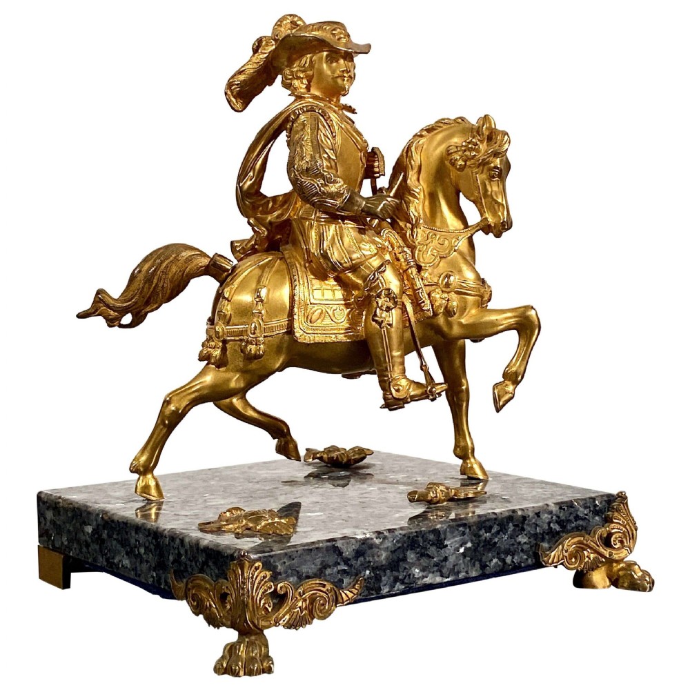 A gilt bronze equestrian statuette depicting King Charles I mounted on horseback, resting on a square grey marble base with metal corner feet.