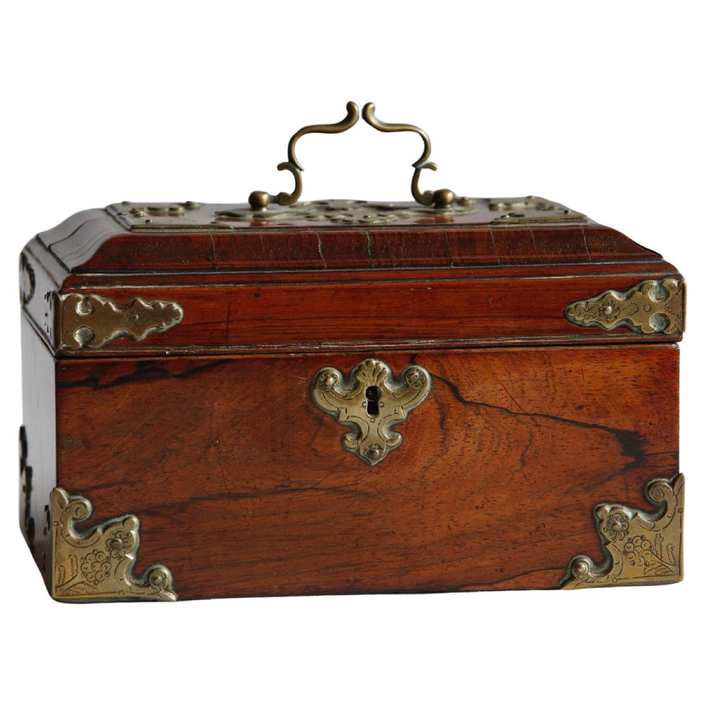A George II padouk wood tea caddy featuring brass corner mounts, an ornate keyhole escutcheon, and a top carrying handle.