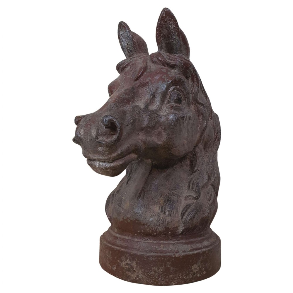A dark brown cast iron sculpture of a horse head with detailed mane features mounted on a circular pedestal base.