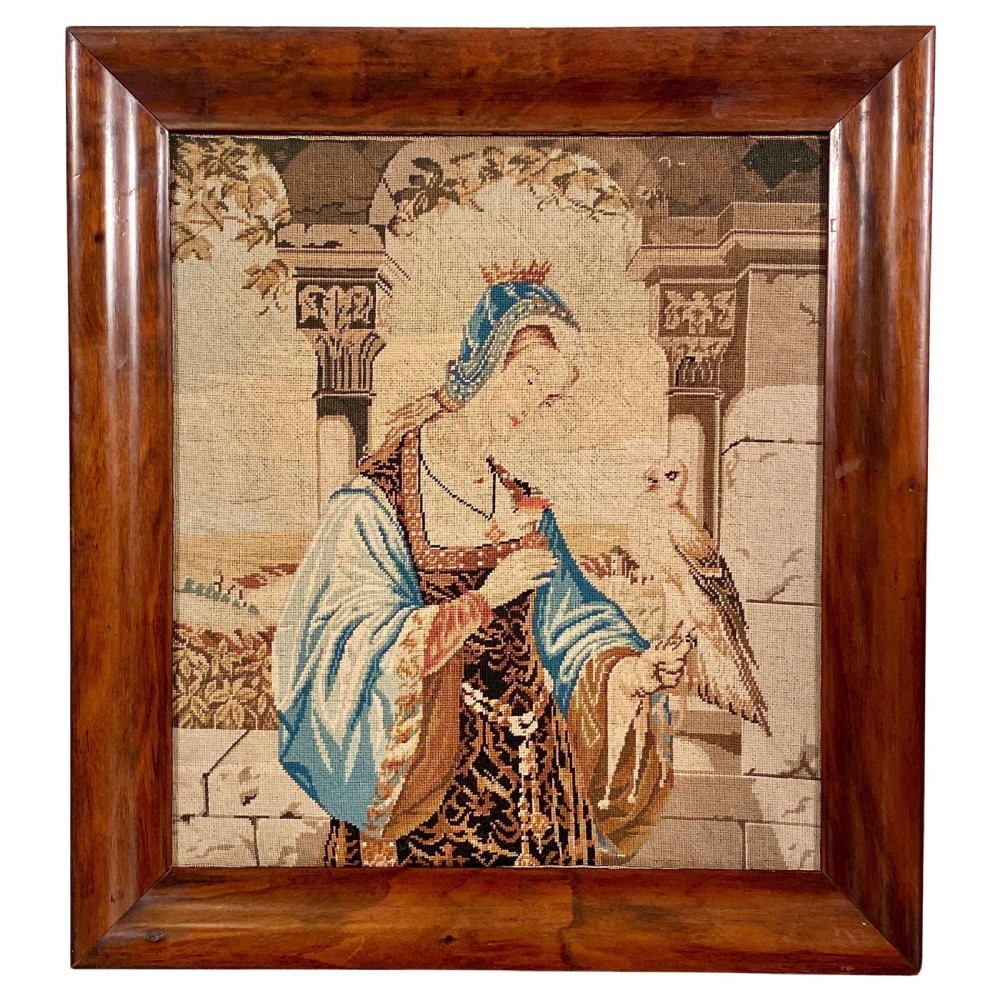 A framed late nineteenth-century wool needlepoint tapestry depicting a woman in historical dress holding a falcon, enclosed in a wide polished wooden frame.