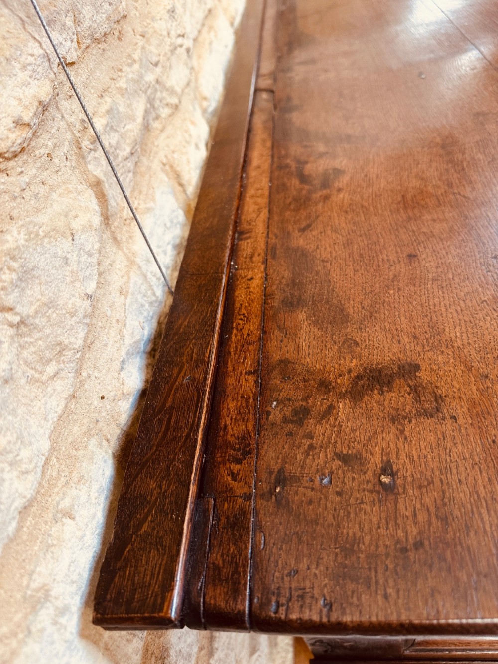 An 18th-century dark oak dresser base featuring three drawers with brass handles and shaped silhouette legs. View VIII