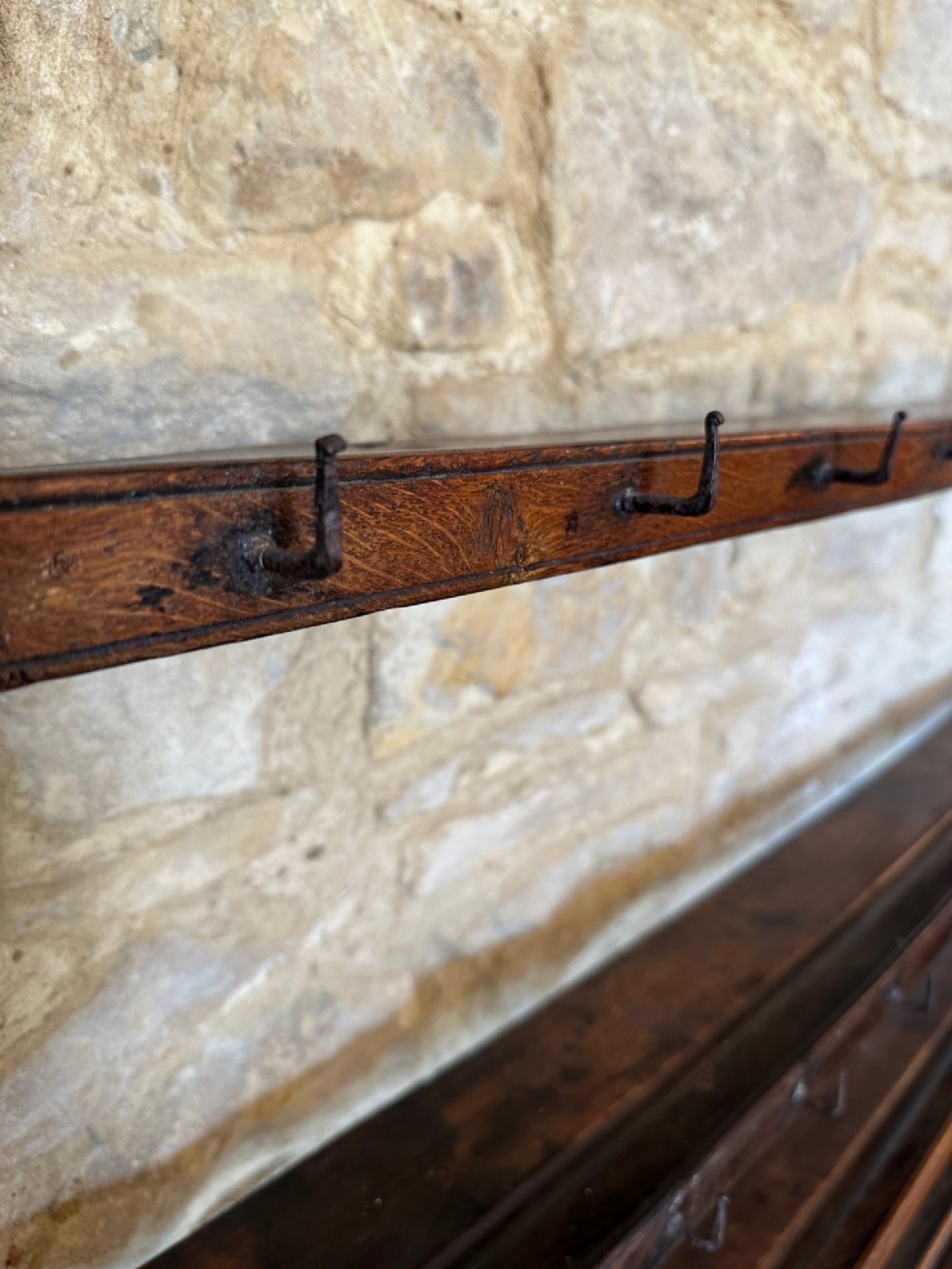 An 18th-century oak potboard dresser featuring an upper open rack with multiple shelves and cup hooks above three frieze drawers and an open lower potboard shelf. View V