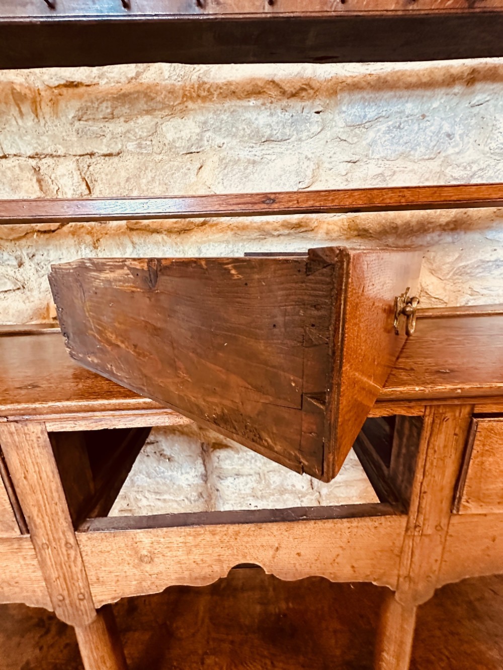 An 18th-century oak potboard dresser featuring an upper open rack with multiple shelves and cup hooks above three frieze drawers and an open lower potboard shelf. View XI