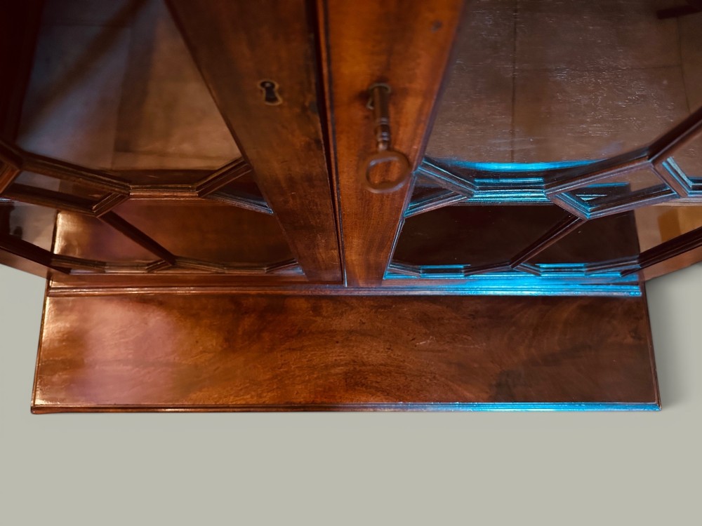 An antique mahogany bookcase on chest featuring a two-door astragal glazed upper display section and three long drawers with decorative brass handles below. View VI