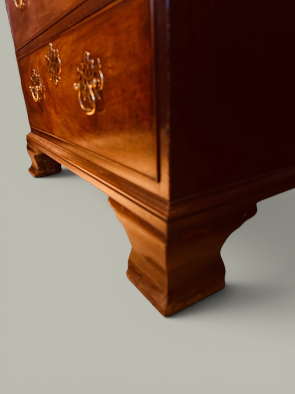 An antique mahogany bookcase on chest featuring a two-door astragal glazed upper display section and three long drawers with decorative brass handles below. View VII