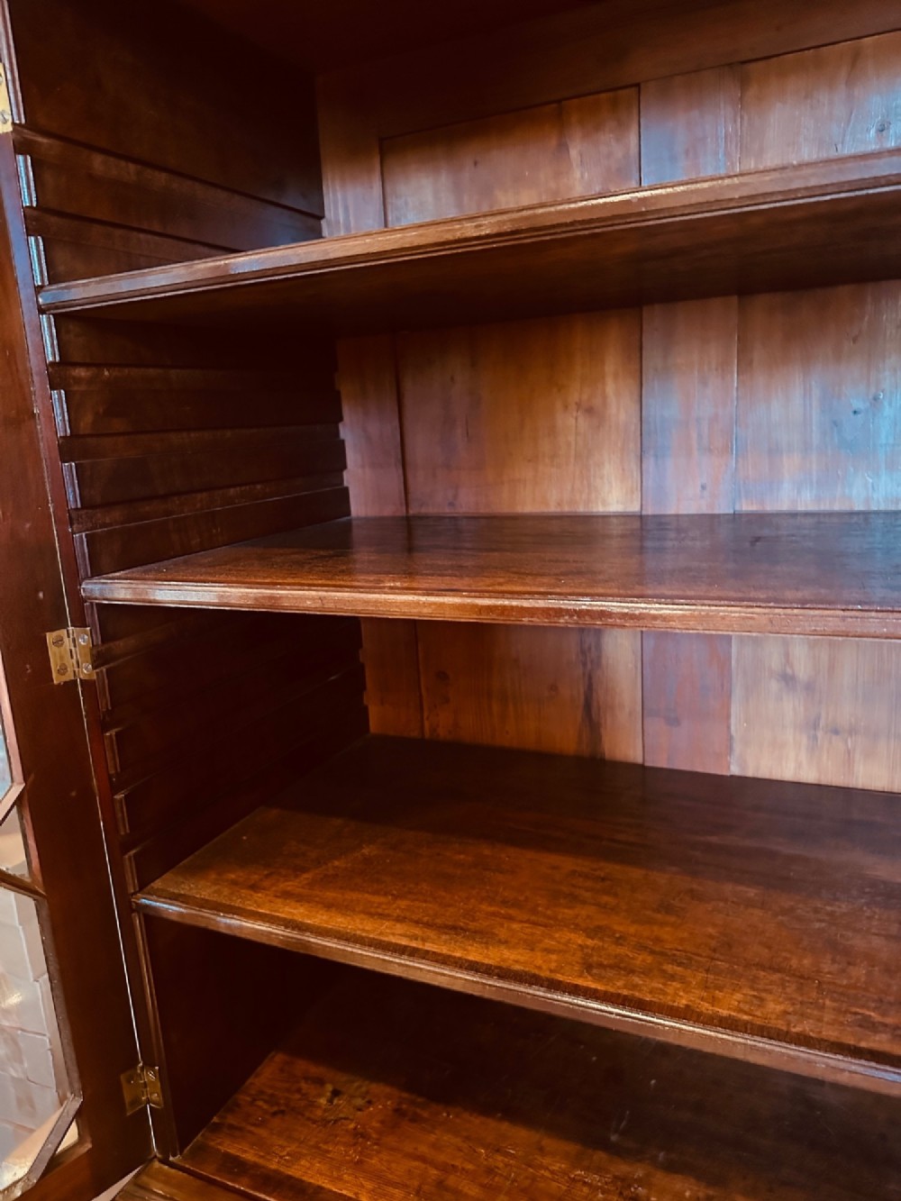An antique mahogany bookcase on chest featuring a two-door astragal glazed upper display section and three long drawers with decorative brass handles below. View VIII