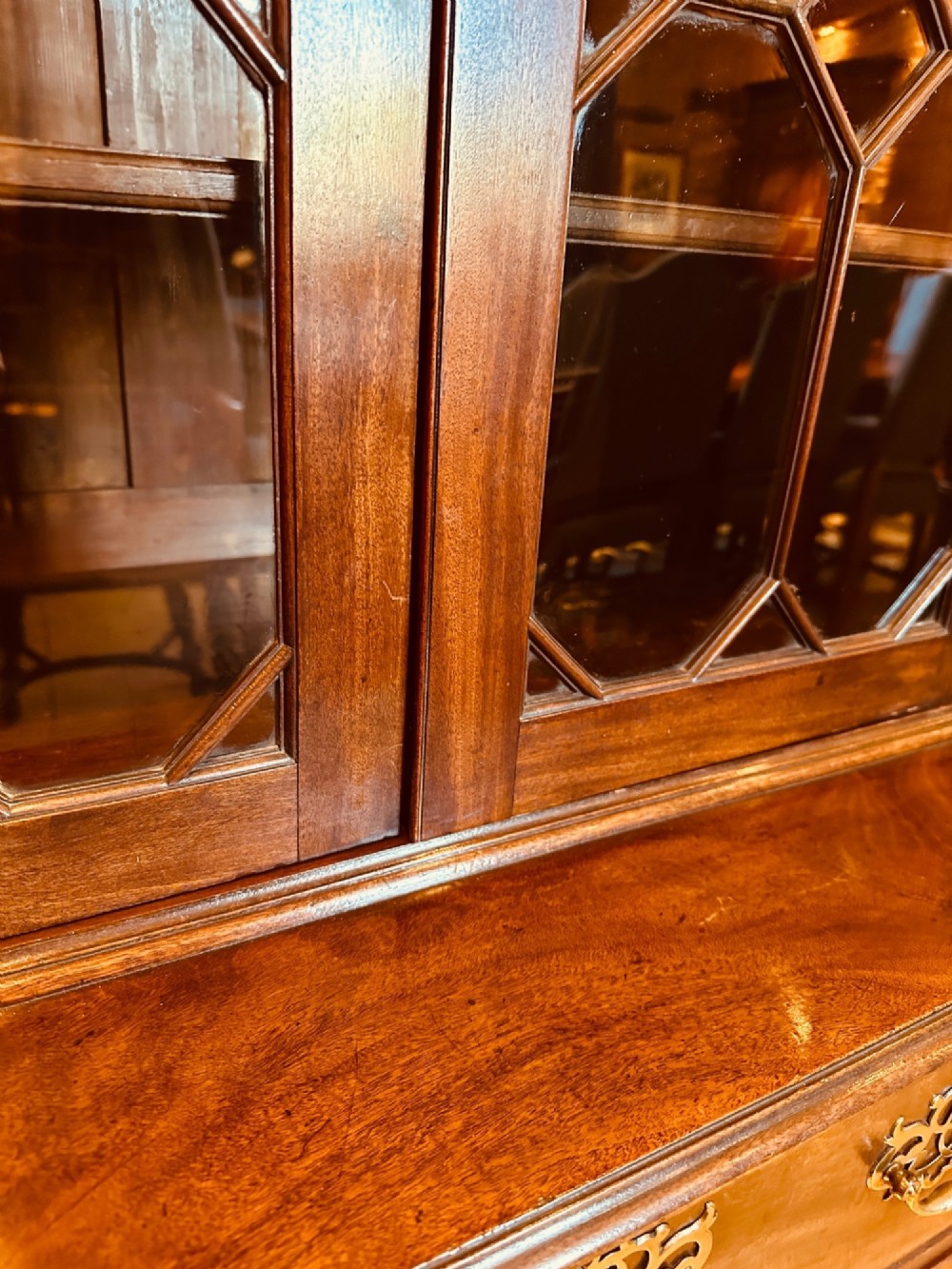 An antique mahogany bookcase on chest featuring a two-door astragal glazed upper display section and three long drawers with decorative brass handles below. View IX