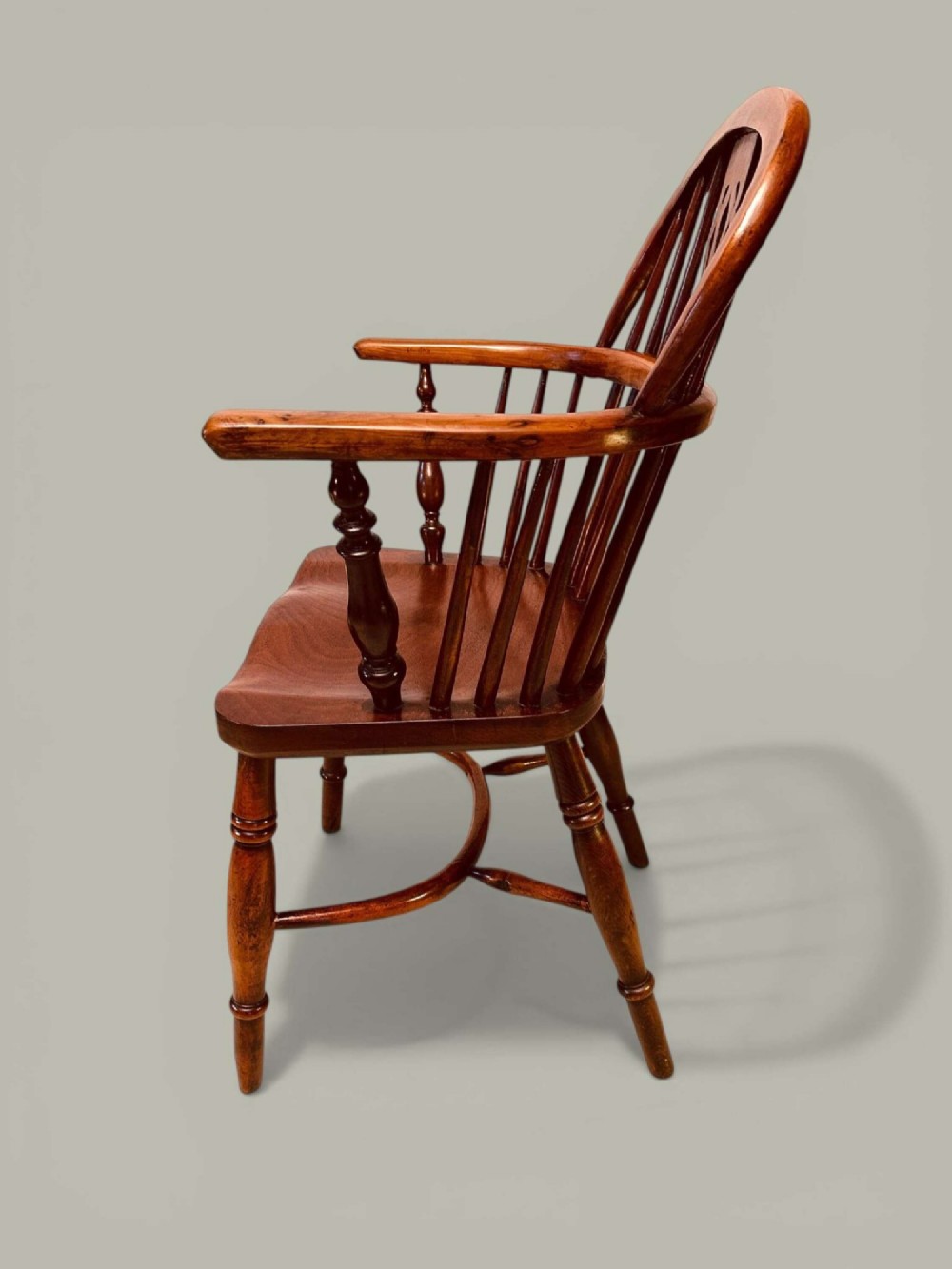A mid-19th-century Windsor armchair crafted from polished yew and elm wood, featuring a hoop back, a pierced central splat, swept arms, and turned legs. View V